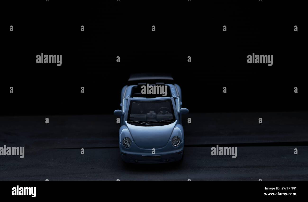 coche azul miniatura sobre un fondo oscuro en la foto en un ligero ángulo desde la parte superior de la parte delantera Foto de stock