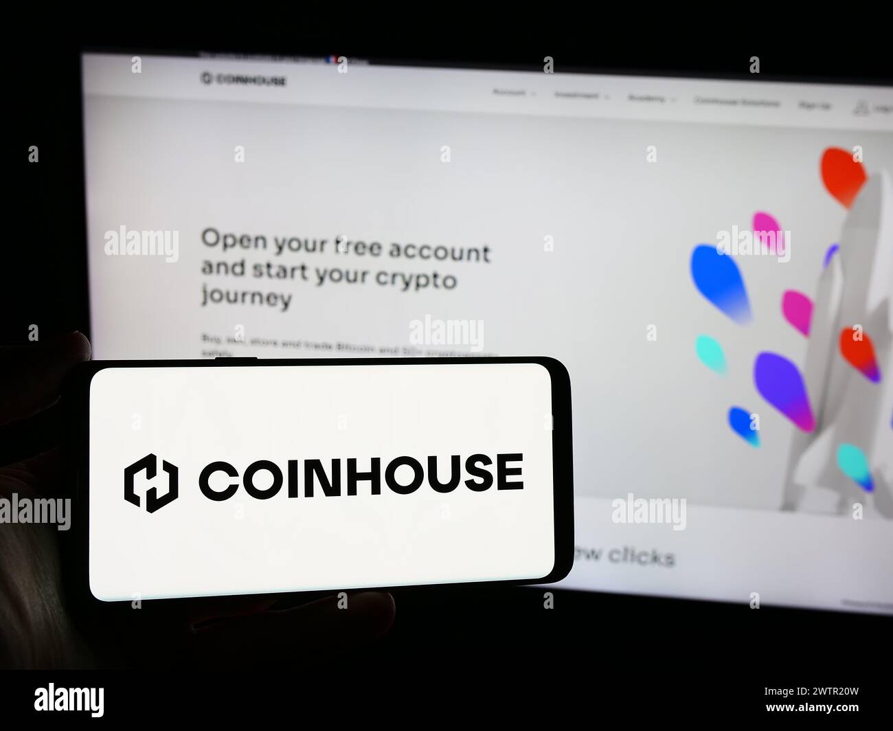 Persona que sostiene el teléfono inteligente con el logotipo de la empresa francesa de criptoinversión Coinhouse SAS frente al sitio web. Enfoque en la pantalla del teléfono. Foto de stock