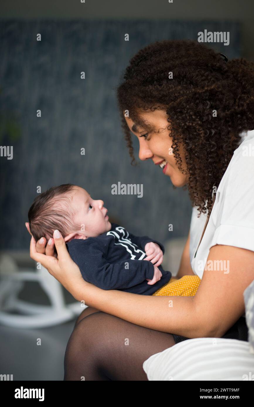 Una joven madre que aprecia un momento tierno con su bebé recién nacido. Foto de stock