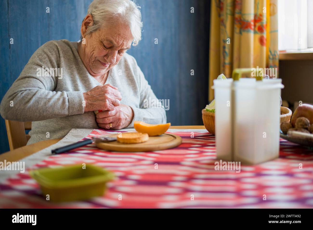 Mujer anciana disfrutando de un momento tranquilo antes de una comida. Foto de stock