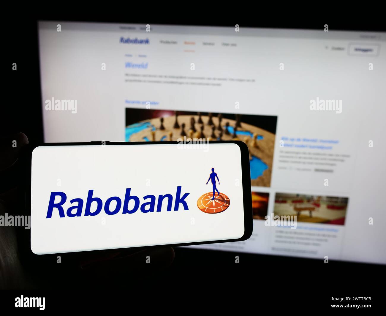 Persona que sostiene el teléfono móvil con el logotipo de la empresa bancaria holandesa Cooperatieve Rabobank UA frente a la página web del negocio. Enfoque en la pantalla del teléfono. Foto de stock