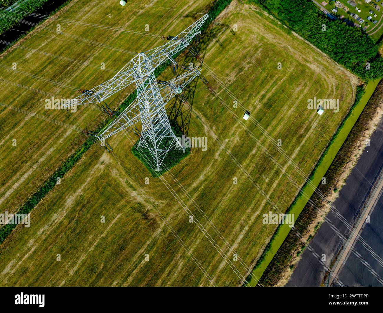 Vista aérea de un imponente pilón eléctrico en medio de campos verdes Foto de stock