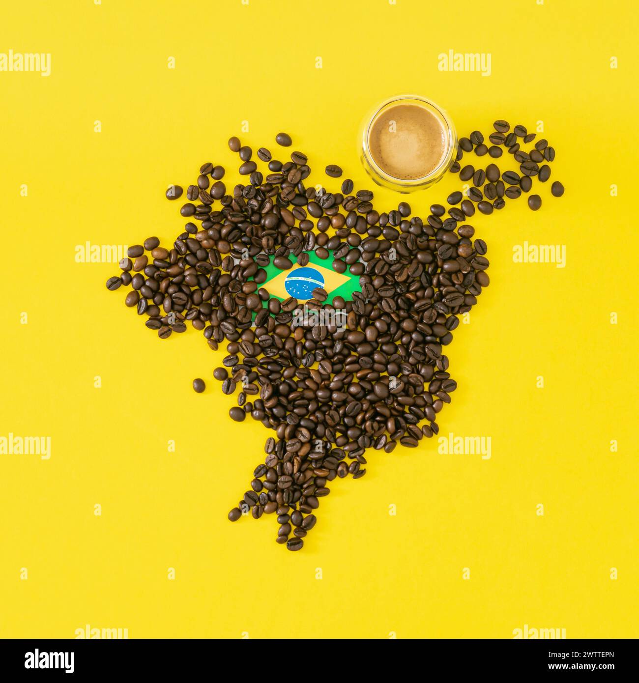 Composición creativa hecha con taza de café, mapa de Brasil hecho con granos de café tostados y bandera brasileña sobre fondo amarillo. Diseño mínimo. Foto de stock