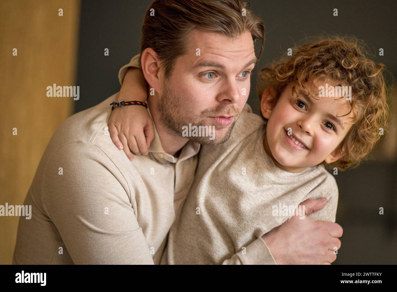 Momento cálido y cariñoso mientras un padre abraza a su pequeño hijo con una sonrisa amorosa. Foto de stock