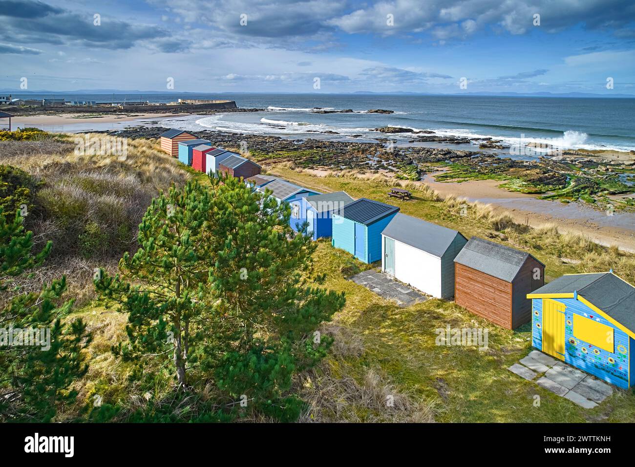 Hopeman Moray Coast Scotland hilera de coloridas cabañas de playa o chalets con vistas a las murallas del puerto y la playa y el mar Foto de stock