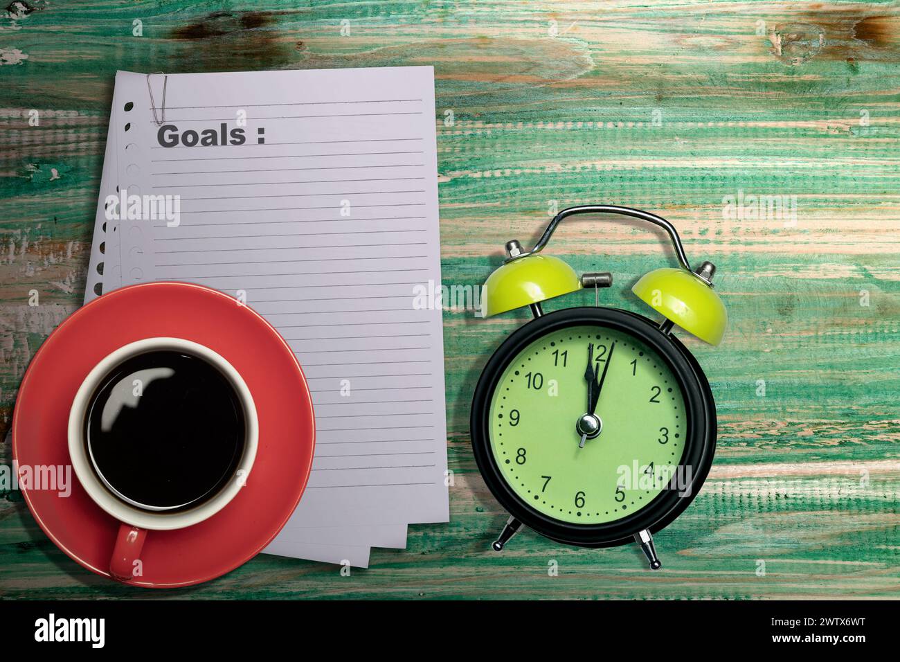 Pila de papel con el texto de los objetivos y una taza de café con un reloj despertador en la mesa. Planificación y concepto de objetivo Foto de stock