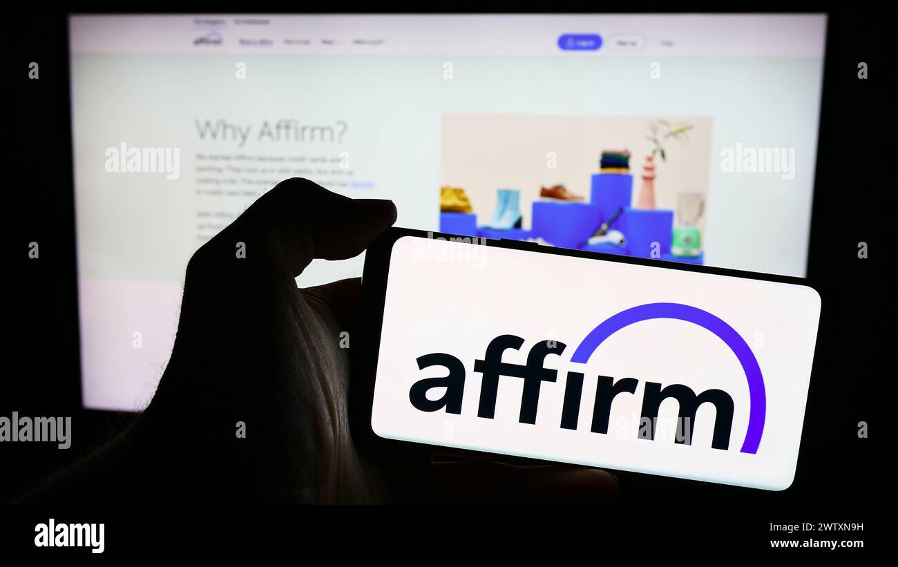 Persona que sostiene el teléfono celular con el logotipo de la compañía fintech de EE.UU. Affirm Holdings Inc. Frente a la página web del negocio. Enfoque en la pantalla del teléfono. Foto de stock