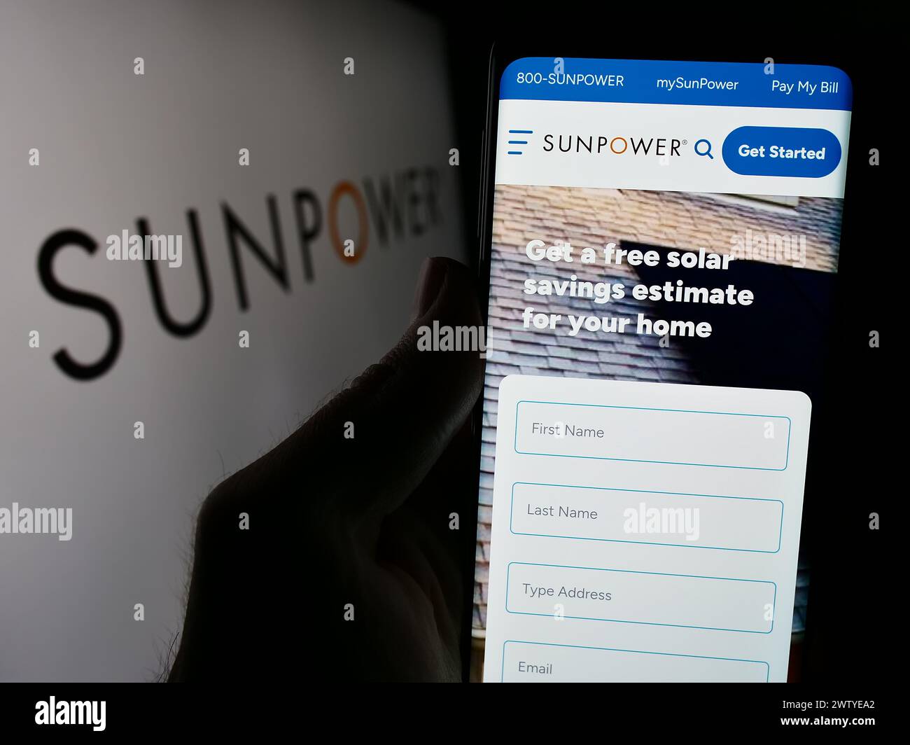 Persona que sostiene el teléfono celular con la página web de la compañía fotovoltaica estadounidense SunPower Corporation frente al logotipo. Enfoque en el centro de la pantalla del teléfono. Foto de stock