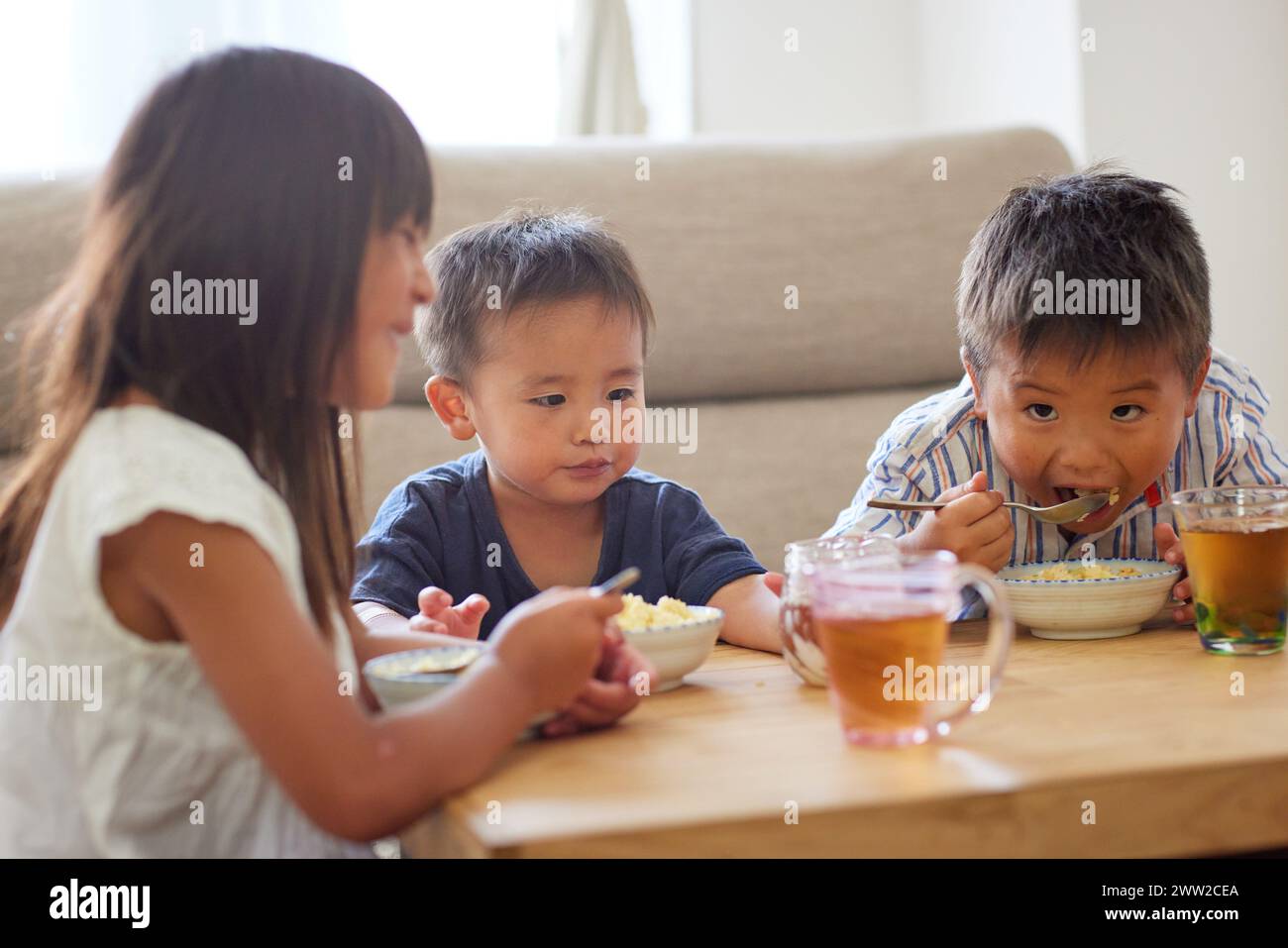 Niños sentados en una mesa comiendo comida Foto de stock