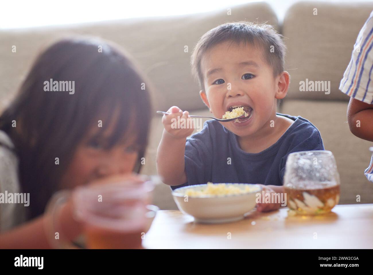 Niño sentado en una mesa comiendo comida Foto de stock