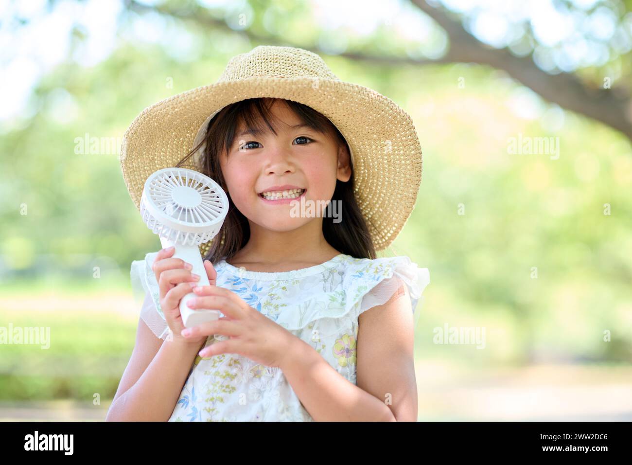 Una niña pequeña en un sombrero sosteniendo un ventilador Foto de stock