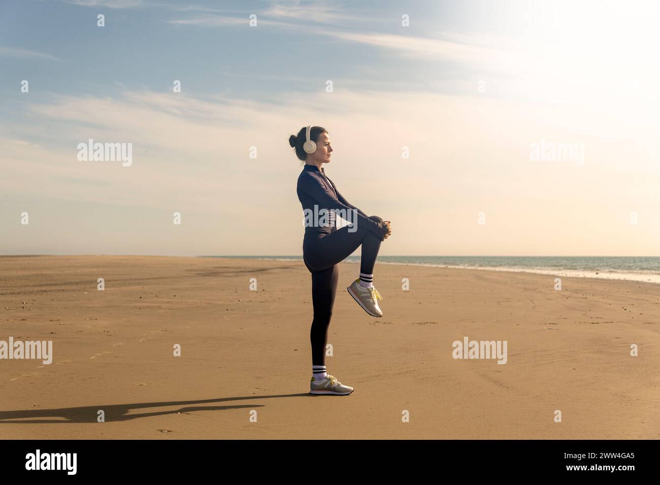 Mujer haciendo ejercicios de estiramiento de piernas en la playa. Rutina de ejercicios matutinos Foto de stock