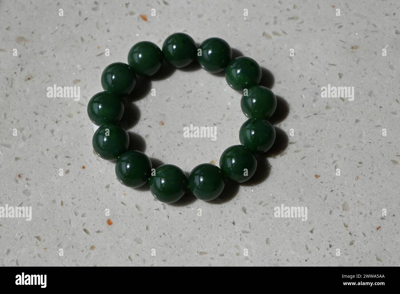 Pulsera de mano verde hecha de jade Hotan sobre el fondo blanco Foto de stock