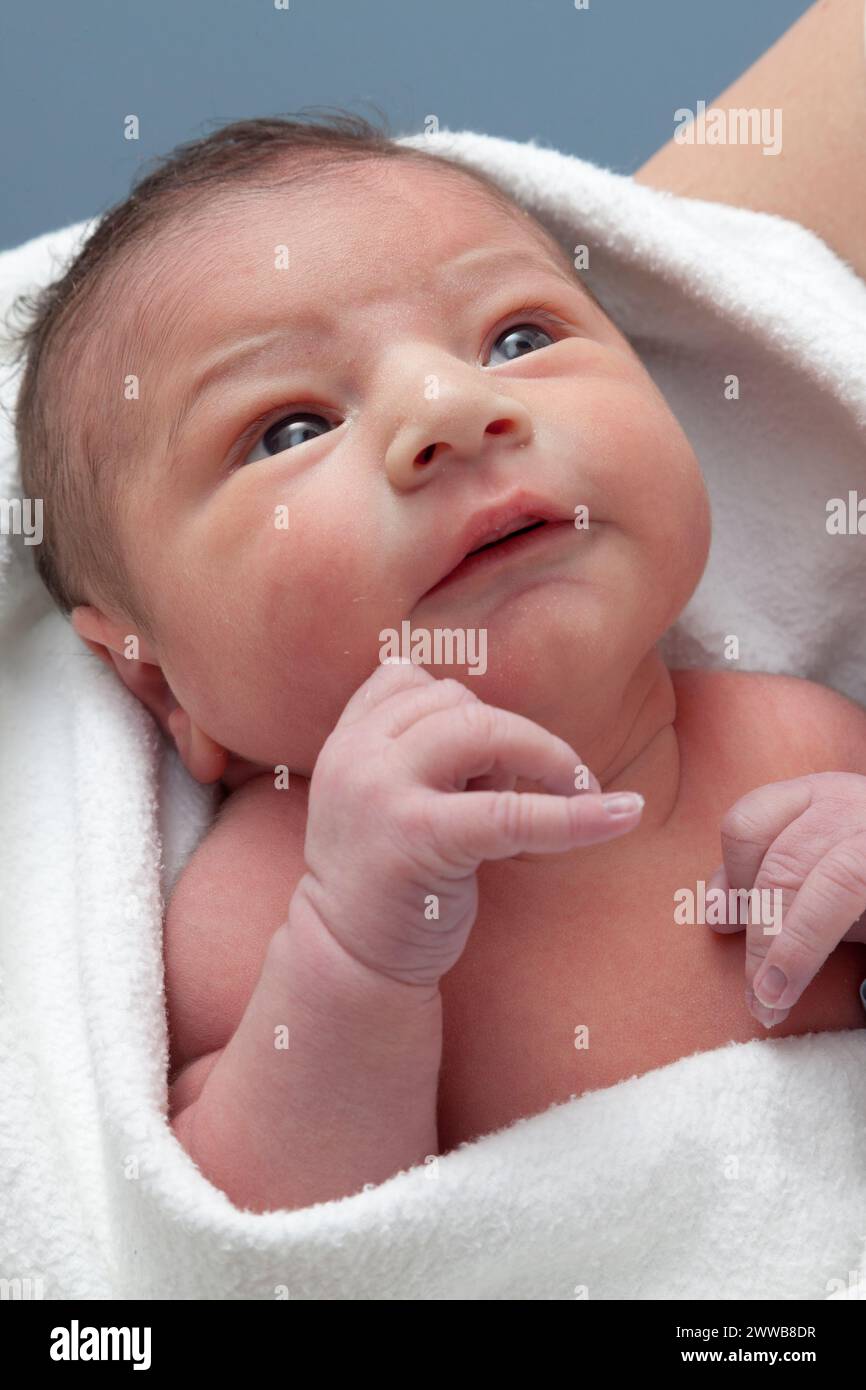 Cara de recién nacido despierto (3 días de edad) en una toalla de baño. Foto de stock