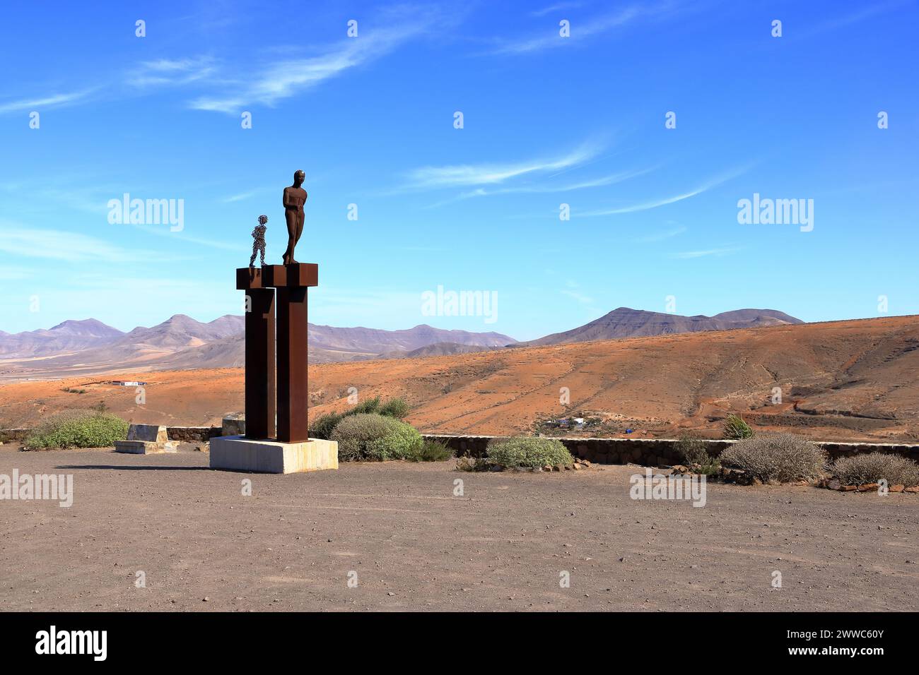 20 de noviembre de 2023 - Betancuria, Fuerteventura en España: Estatua del caminante y su hijo en Mirador de Valle de las Cuevas con tierras volcánicas de montaña Foto de stock