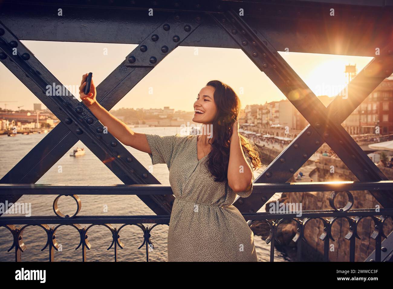 Mujer feliz tomando selfie a través de teléfono inteligente en el puente Dom Luis en Oporto, Portugal Foto de stock
