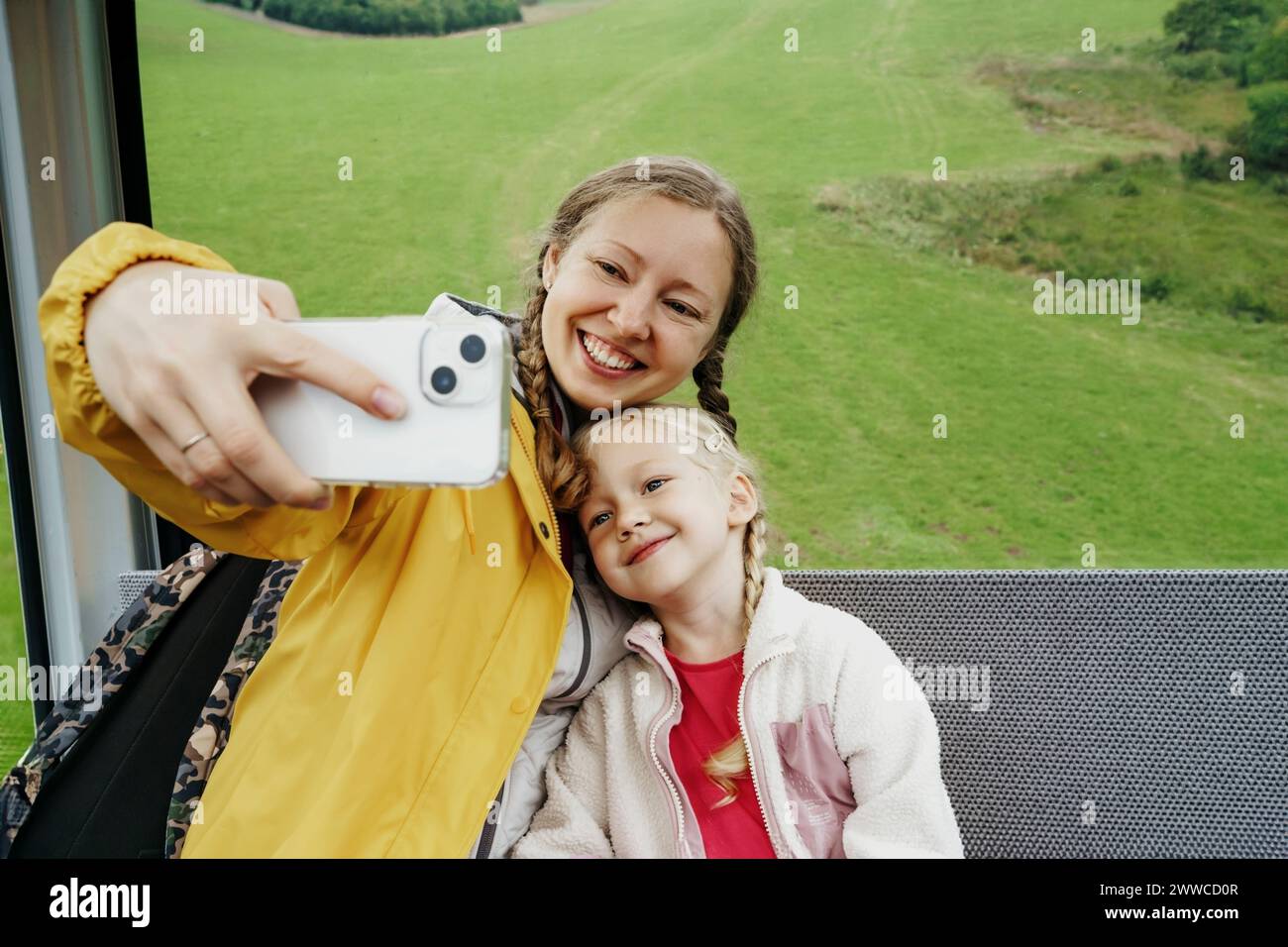 Mujer feliz que toma selfie con la hija a través del teléfono móvil en telesquí Foto de stock