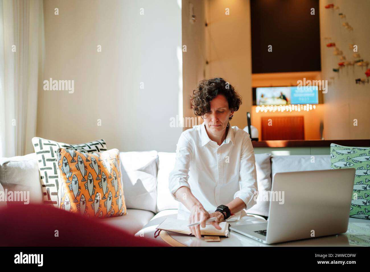 Empresaria con diario y portátil trabajando en el vestíbulo del hotel Foto de stock