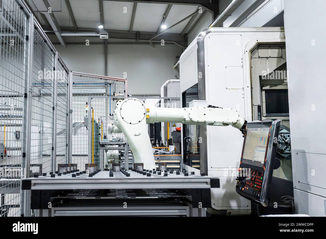 Brazo robótico blanco por maquinaria CNC en el edificio moderno de la fábrica Foto de stock