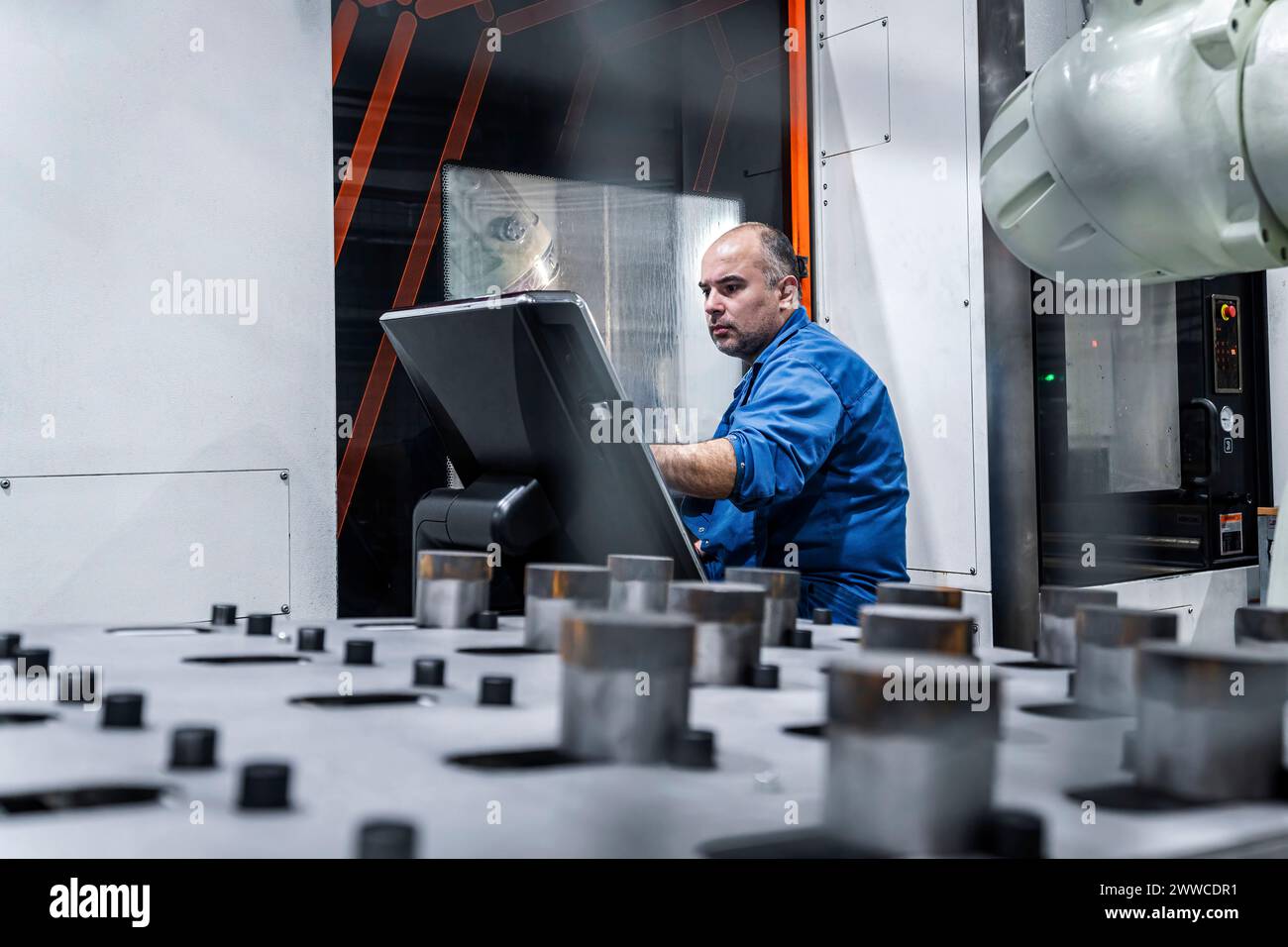 Técnico que opera la máquina CNC en la fábrica moderna Foto de stock