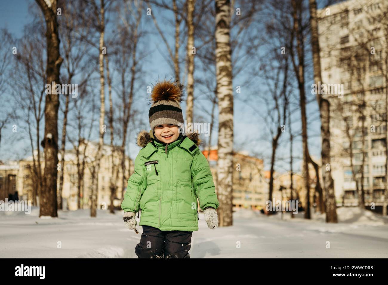 Niño sonriente caminando en la nieve en el parque Foto de stock