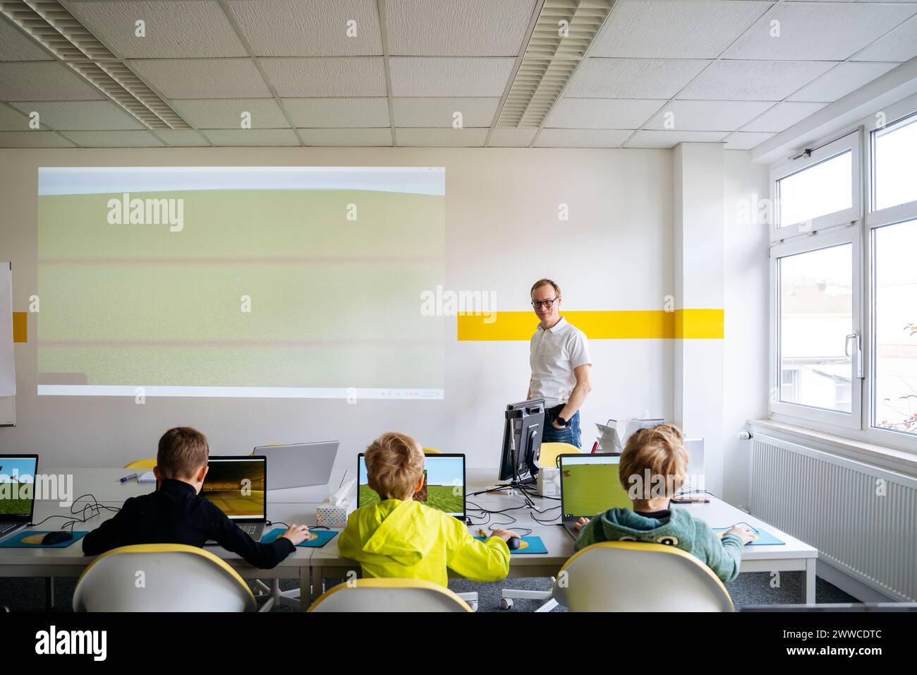 Profesor que enseña a los niños en el aula de informática en la escuela Foto de stock