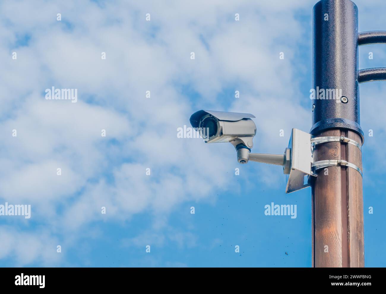 Cámara de vigilancia montada en poste de luz de metal con cielo azul y nubes blancas hinchadas en el fondo en Corea del Sur Foto de stock