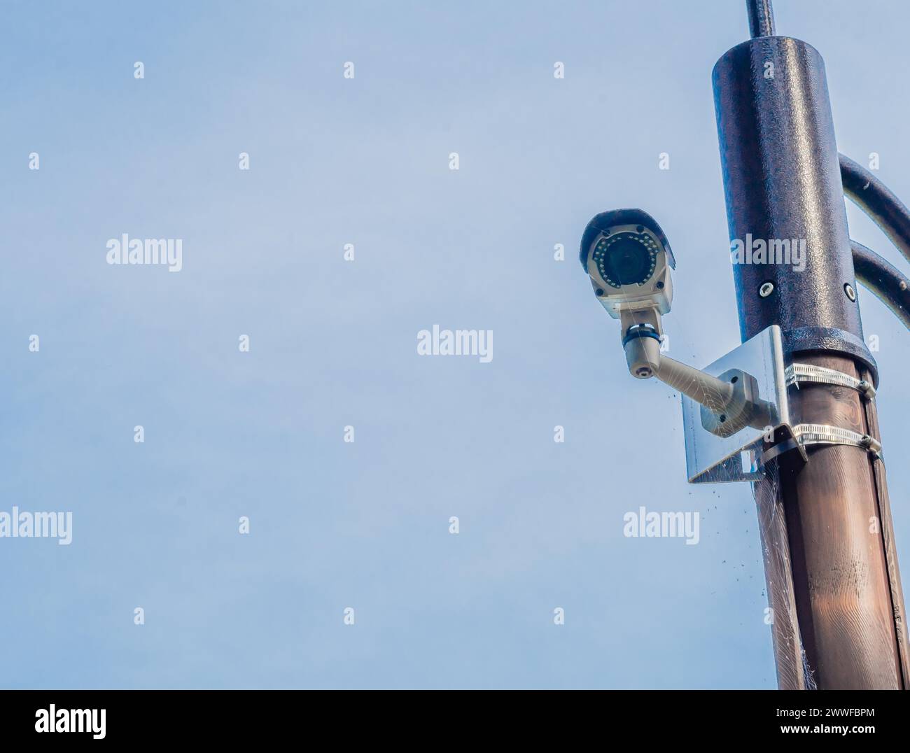Cámara de vigilancia montada en poste de luz de metal con cielo azul y nubes blancas hinchadas en el fondo en Corea del Sur Foto de stock