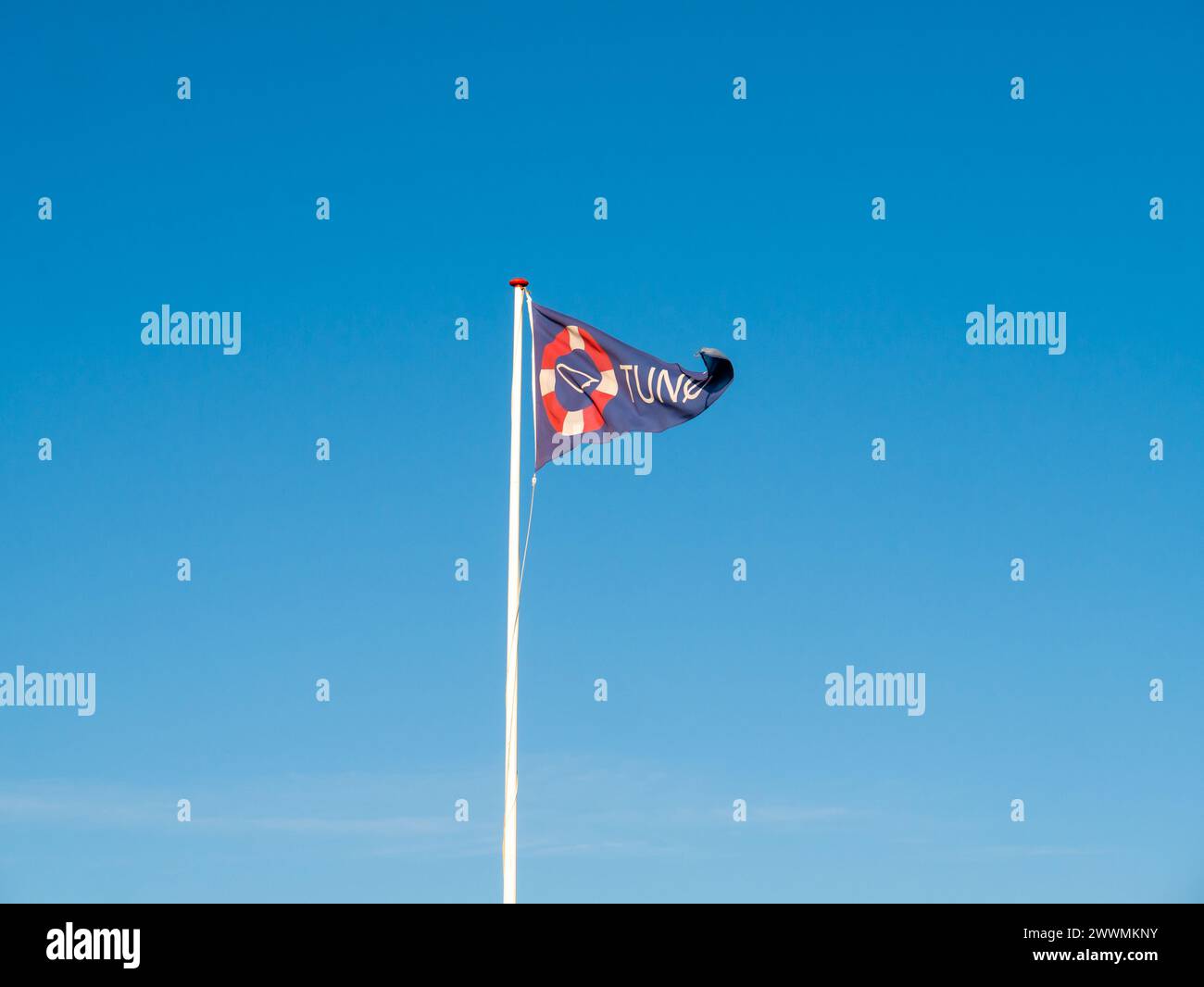 Ondeando bandera triangular con el signo y el nombre de la isla de Tunø contra un cielo azul, Midtjylland, Dinamarca Foto de stock