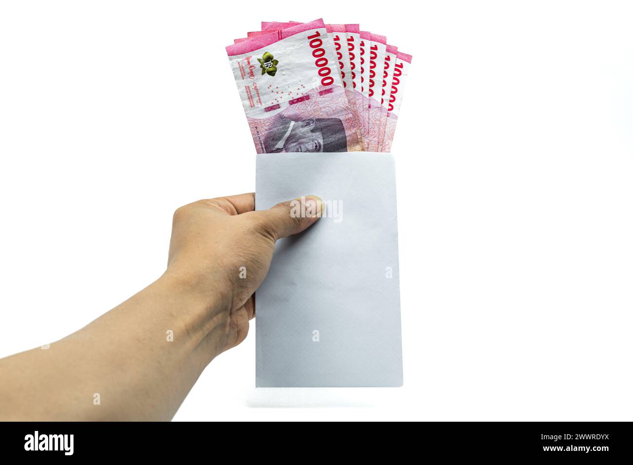 Mano del hombre asiático sosteniendo sobre blanco que contiene la pila de IDR 100.000 efectivo. Moneda de la rupia indonesia Foto de stock