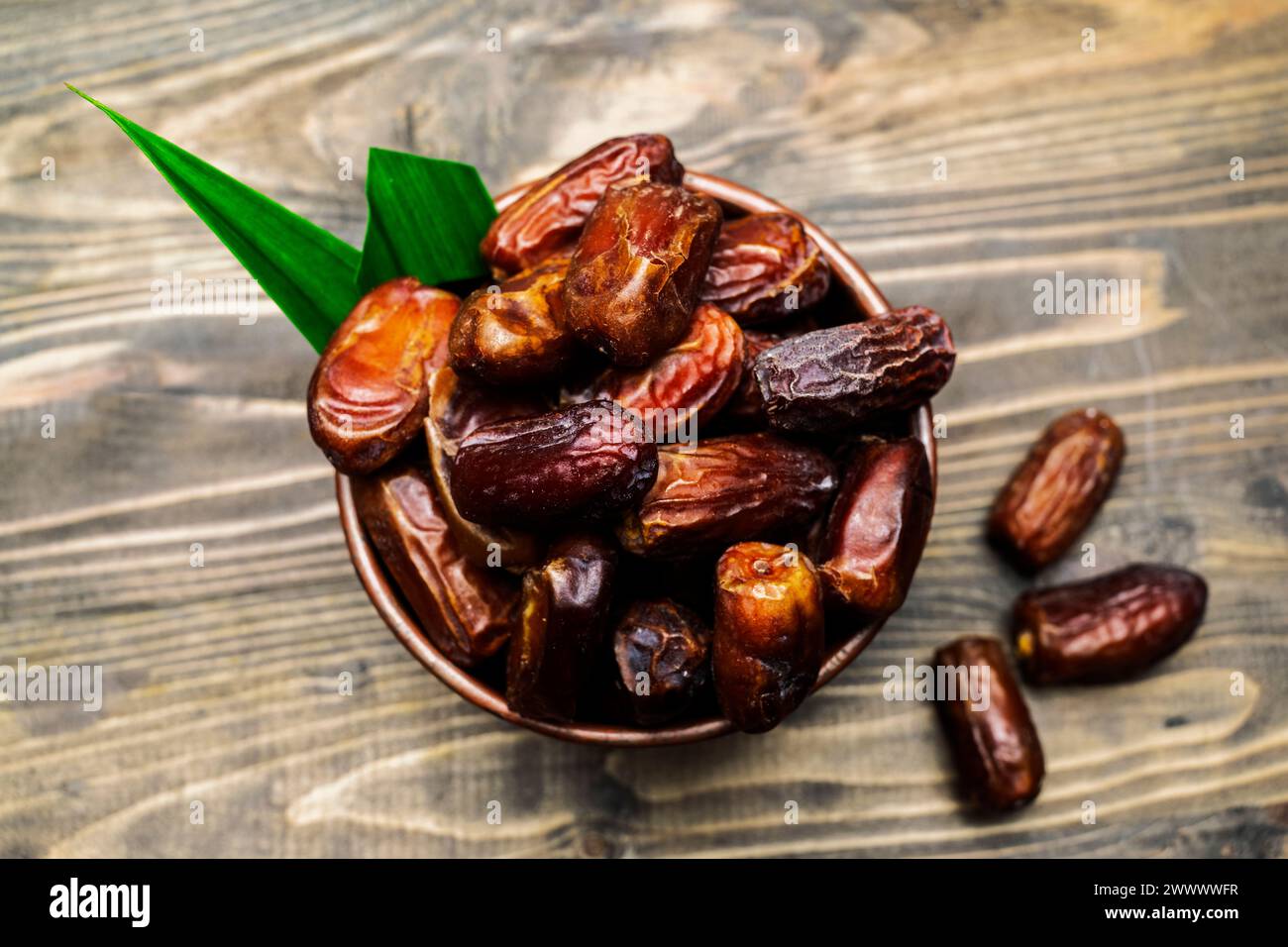 Dátiles secos Fruta para iftar en Ramadán en el tazón en una mesa de madera Foto de stock