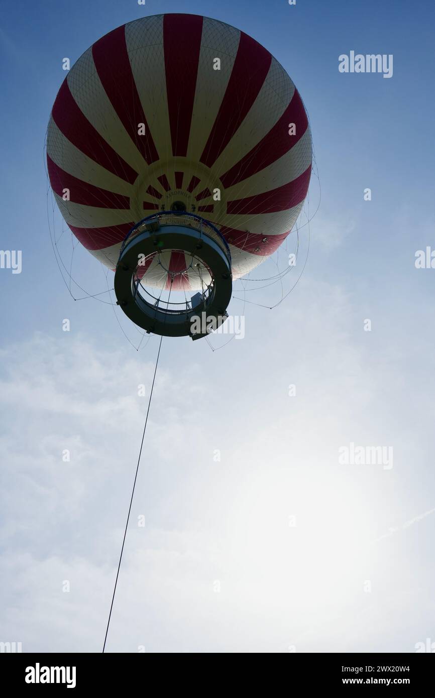 El Aerófilo rojo y blanco terthered globo de aire caliente flotando en lo alto de la ciudad. Foto de stock