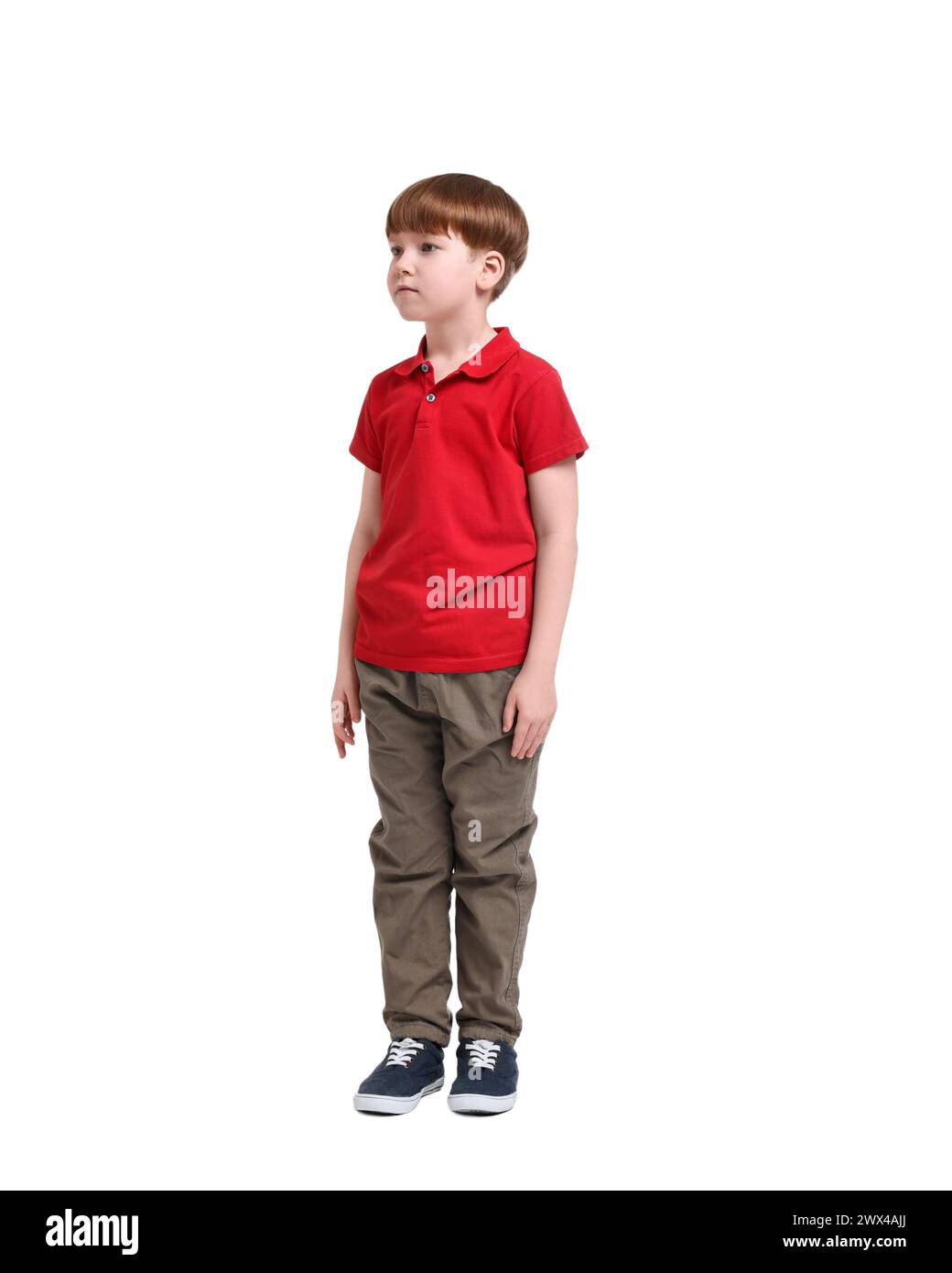 Niño pequeño en camisa polo roja y pantalones beige sobre fondo blanco Foto de stock