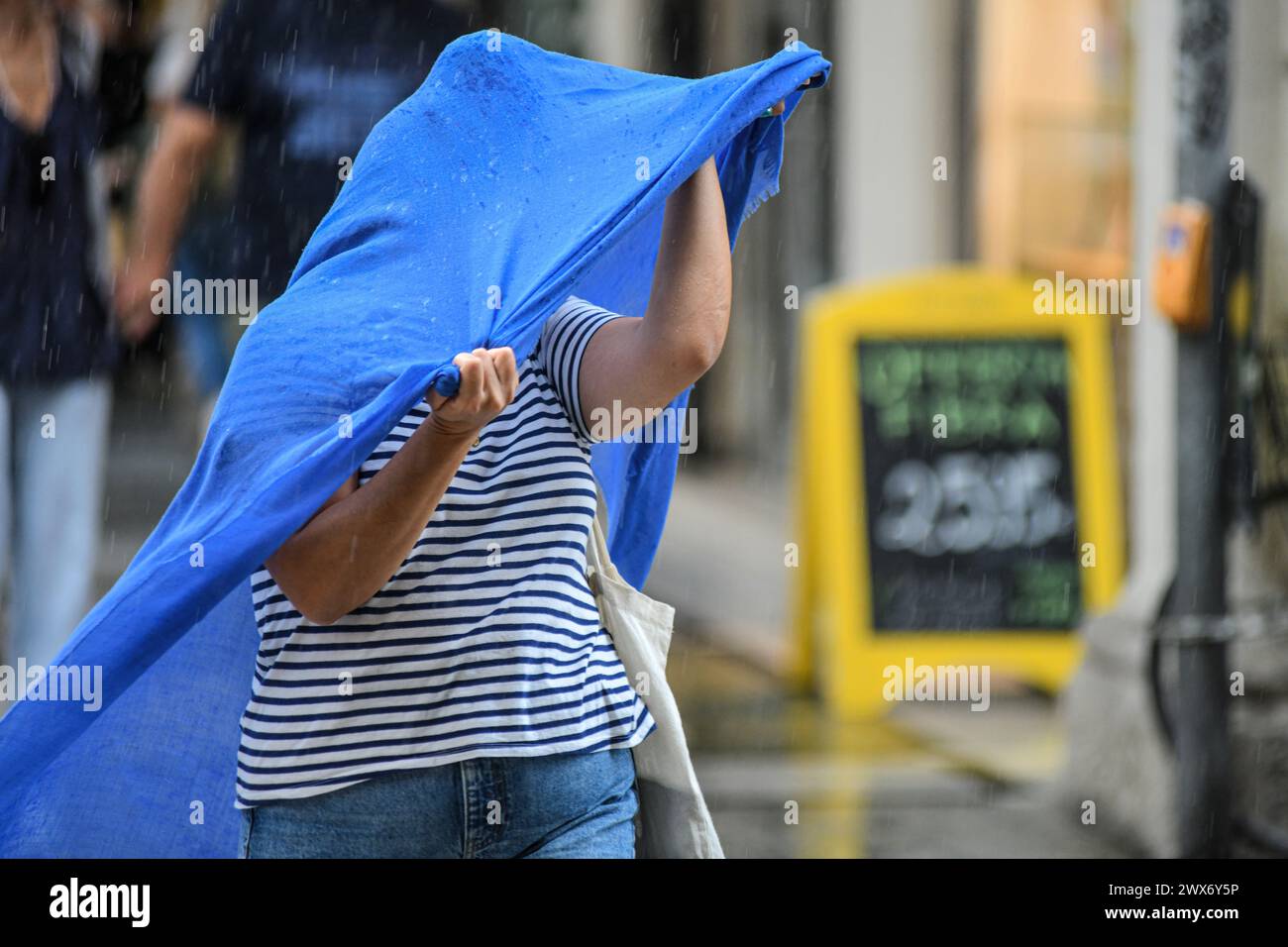 Mujer cruzando la calle bajo la lluvia. Via Ugo Bassi, Bolonia, Italia. Foto de stock