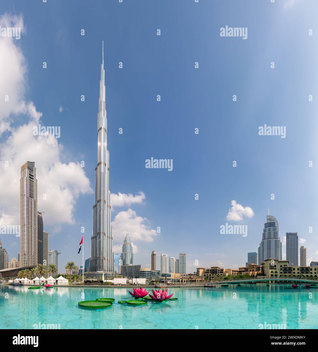 Una imagen del Burj Khalifa que se eleva sobre los edificios cercanos del centro de Dubai y las aguas azules del lago Burj Khalifa. Foto de stock