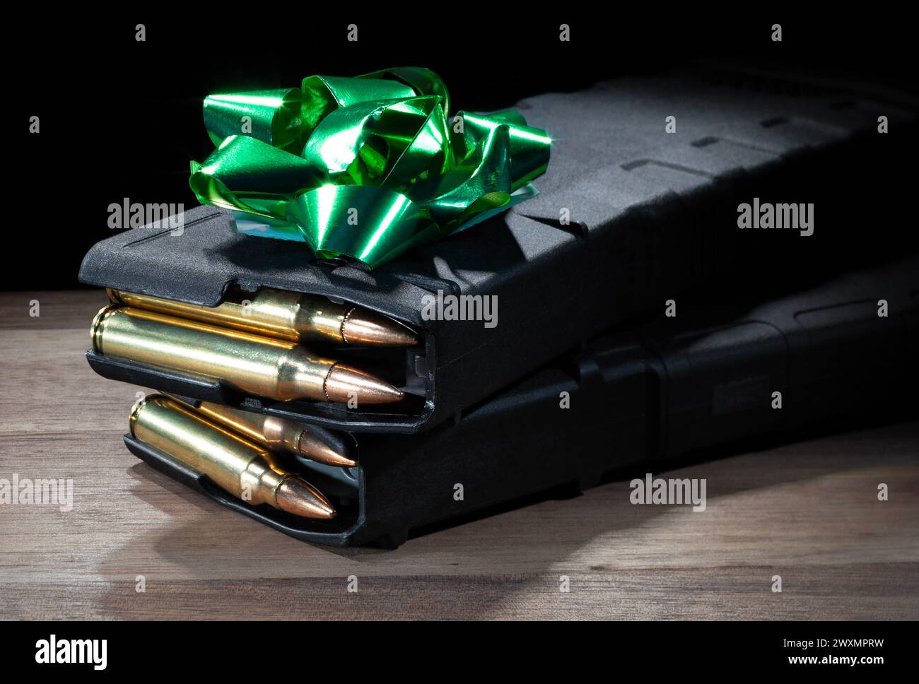 Cargadores de rifle de asalto de alta capacidad cargados con balas y con un arco verde en la parte superior para hacer el regalo perfecto para un propietario de arma de fuego. Foto de stock