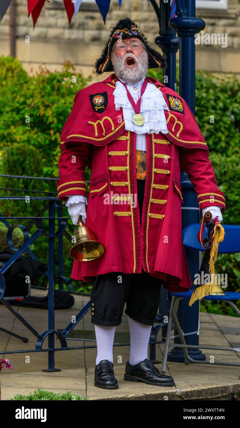 Un criador de pueblo masculino (colorida decoración de criador trenzado rojo) proclamando anuncio y haciendo una fuerte proclamación pública - Ilkley, West Yorkshire Inglaterra, Reino Unido. Foto de stock