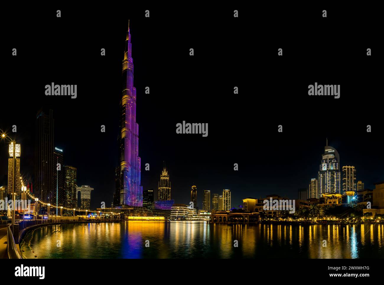 Una imagen del icónico Burj Khalifa con su espectáculo de luces, y los edificios del centro de Dubai y el lago Burj Khalifa, en la noche. Foto de stock