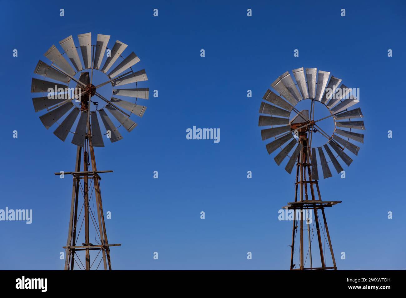 Sección de turbina de dos molinos de viento de estilo antiguo con el cielo azul como fondo. antecedentes. Foto de stock