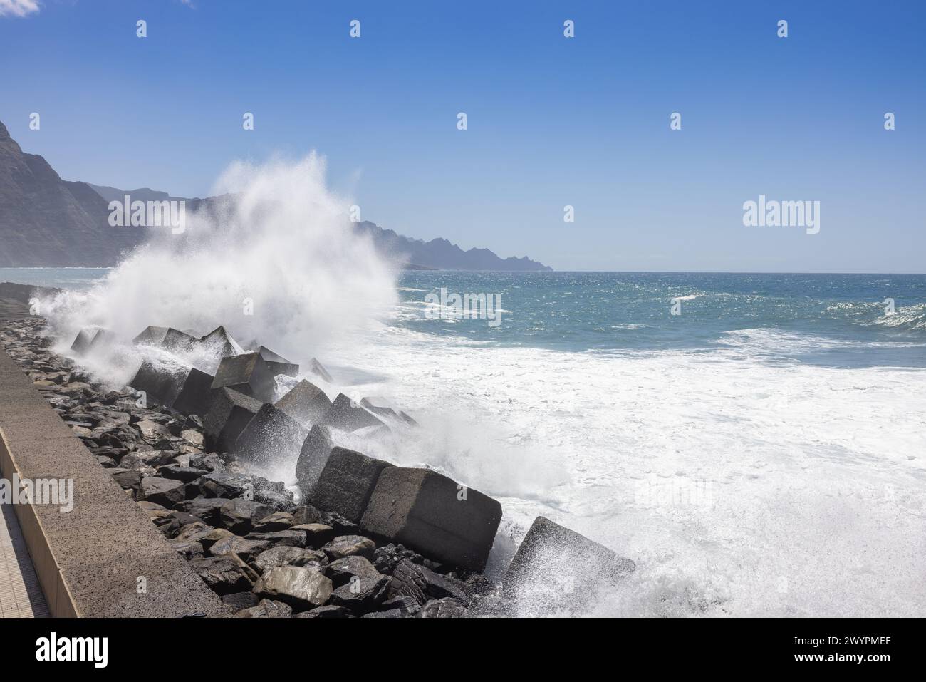 Rompimiento de olas en Puerto de las Nieves en la isla de Gran Canaria en el Océano Atlántico. En el fondo los acantilados de la parte noroeste Foto de stock