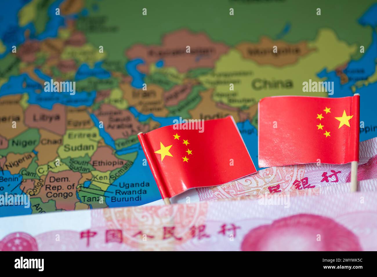 Un concepto chino de inversiones globales en el sur con billetes de banco en yuanes chinos y banderas nacionales sobre un mapa de algunos países en el hemisferio sur. Foto de stock