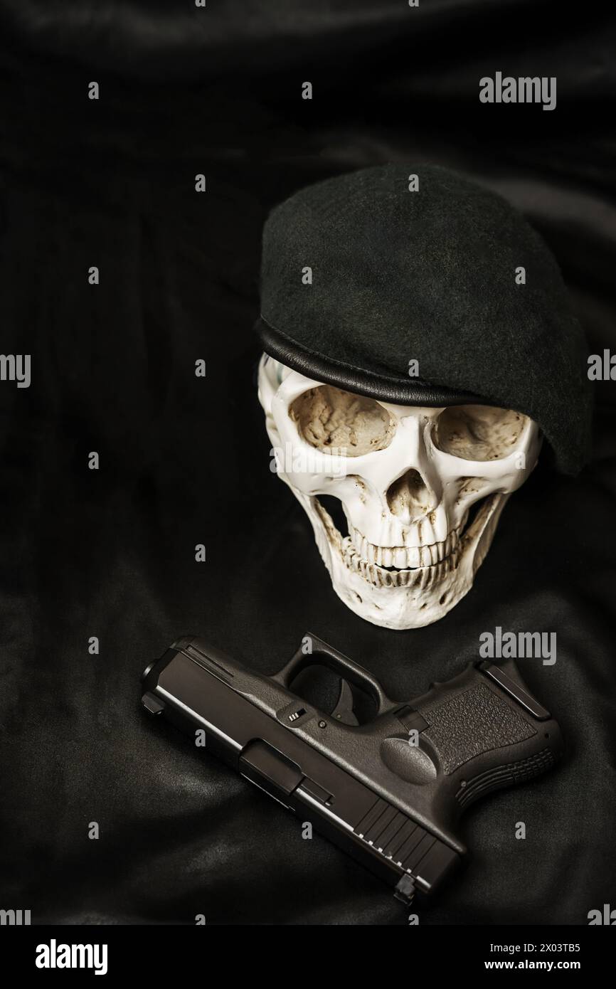 Un cráneo militarizado junto a un cañón de airsoft negro Foto de stock