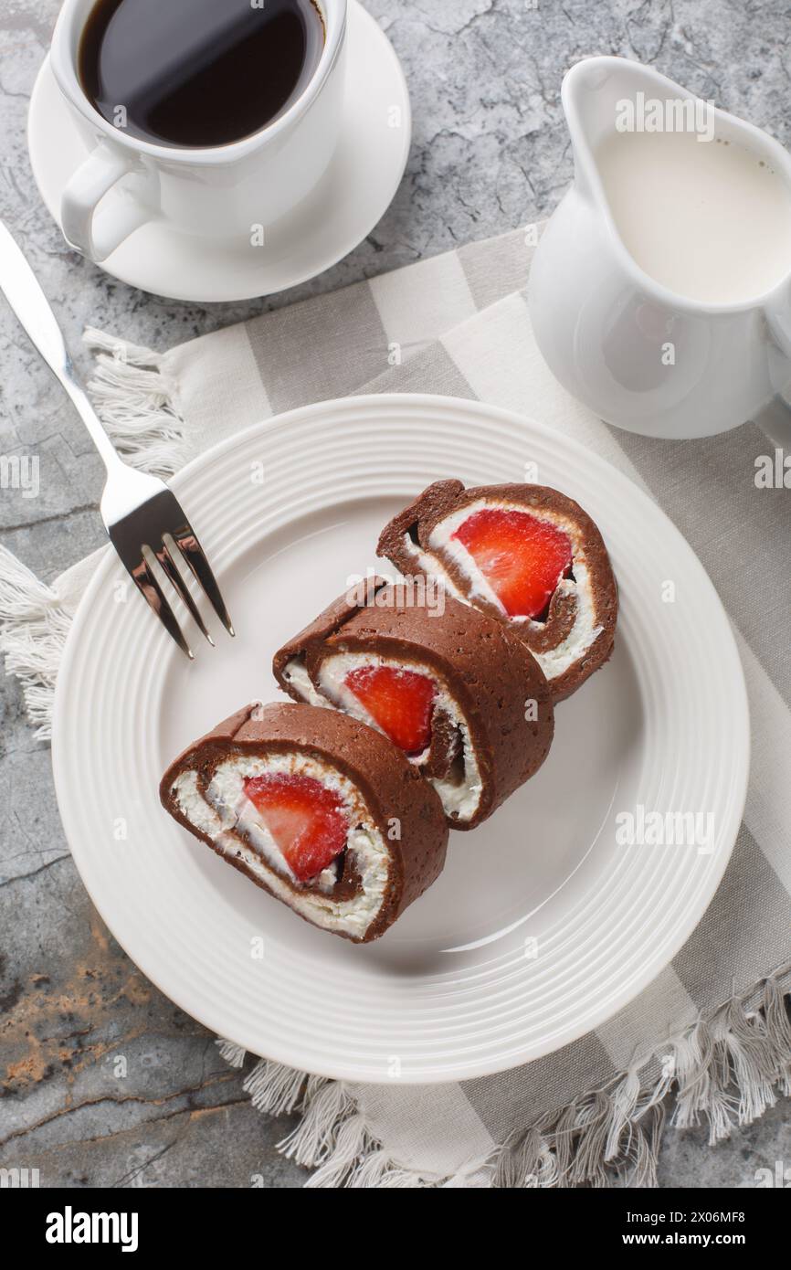 Tarta de queso de pan suizo de chocolate de fresa servida con café de cerca en la mesa. Vista superior vertical desde arriba Foto de stock