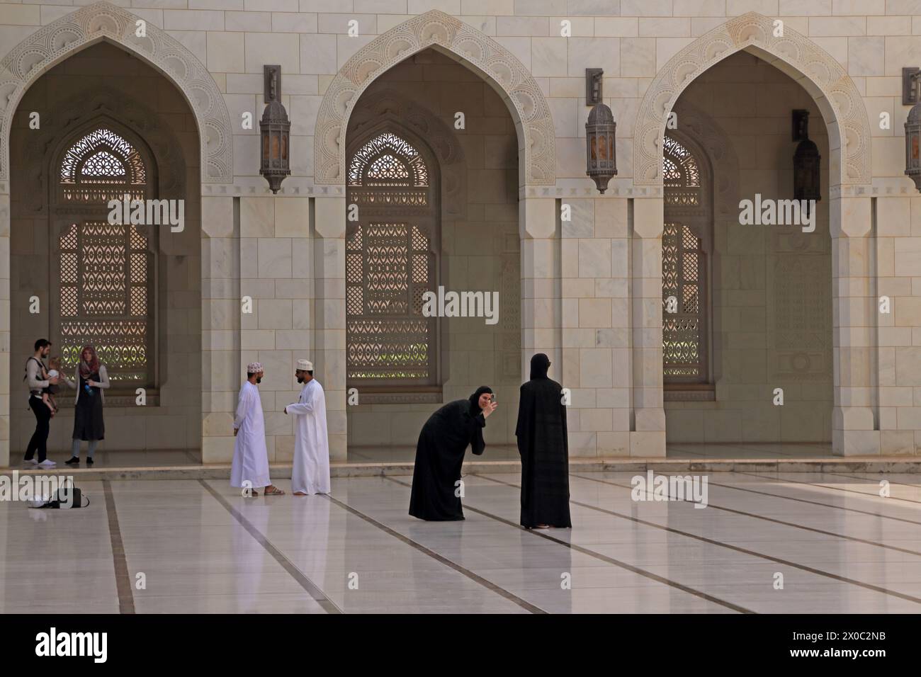Visitantes de la Gran Mezquita del Sultán Qaboos tomando fotografías con Smart Phone en el Patio (Sahn) Mascate Omán Foto de stock