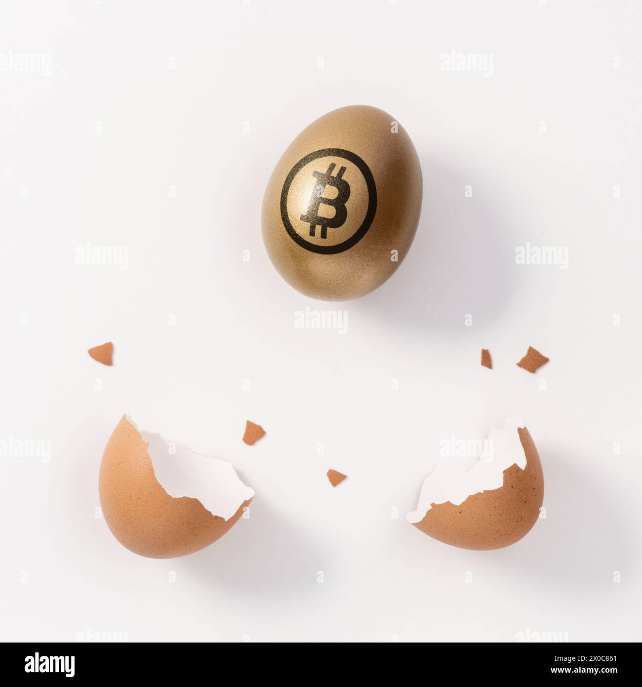 Huevo de oro con un signo de bitcoin y cáscara de huevo sobre fondo blanco. Concepto de inversión mínima. Foto de stock