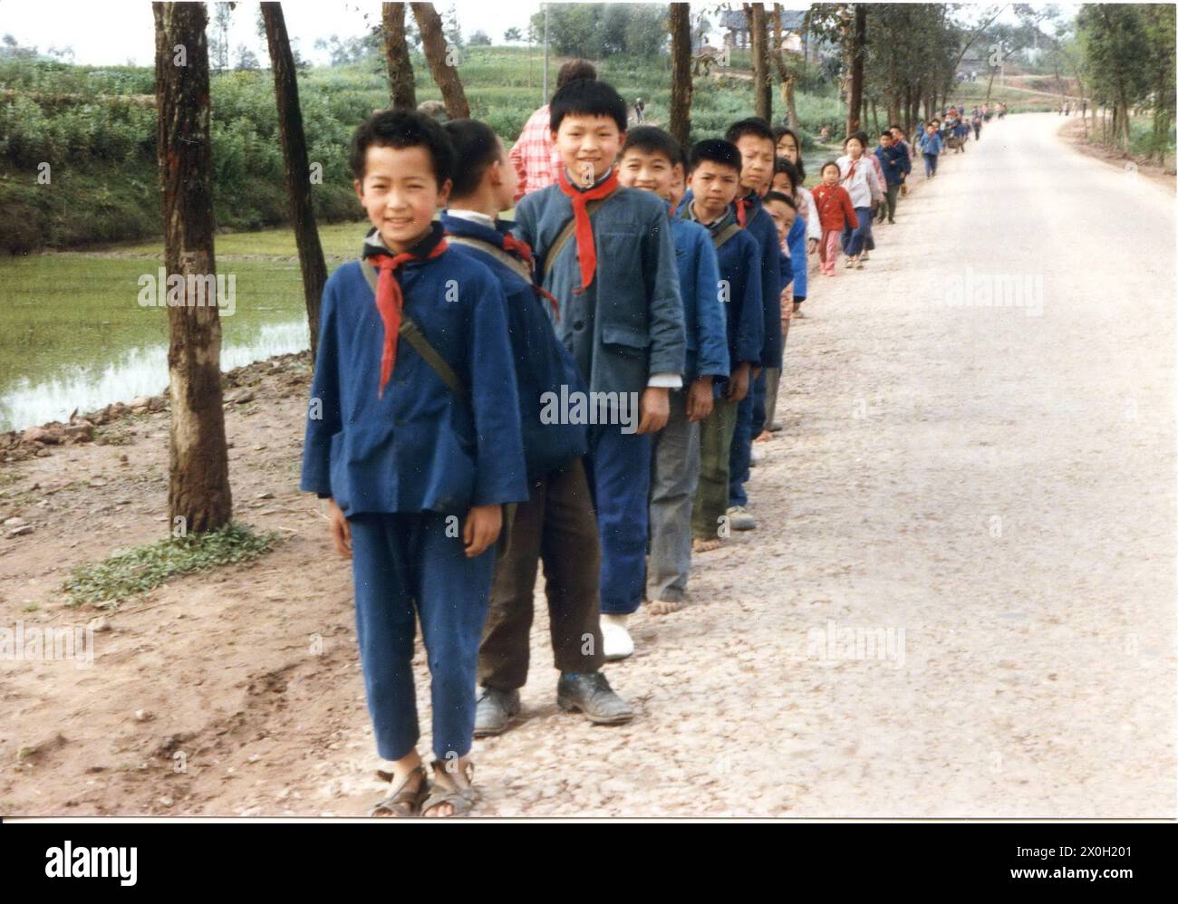 Kinder mit roten Halstüchern und blauem mao-anzug stehen en einer Reihe aufgereiht am Straßenrand in der Nähe von Chongqing en China. (Aufnahmedatum: 01.01.1985-31.12.1985) Foto de stock