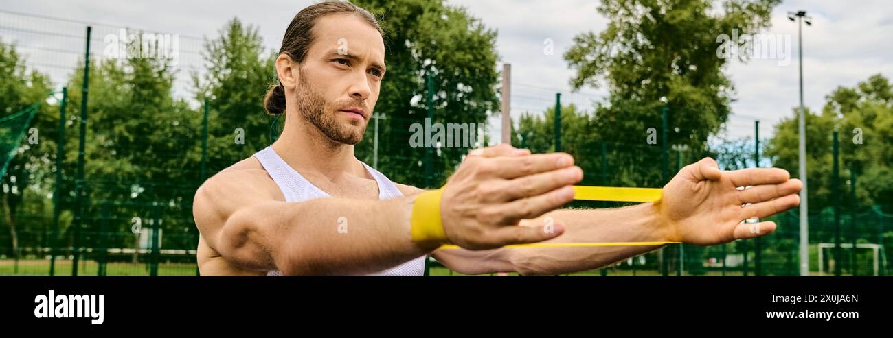 Un hombre sostiene un objeto amarillo vibrante en sus manos, entrenamiento de banda de resistencia Foto de stock