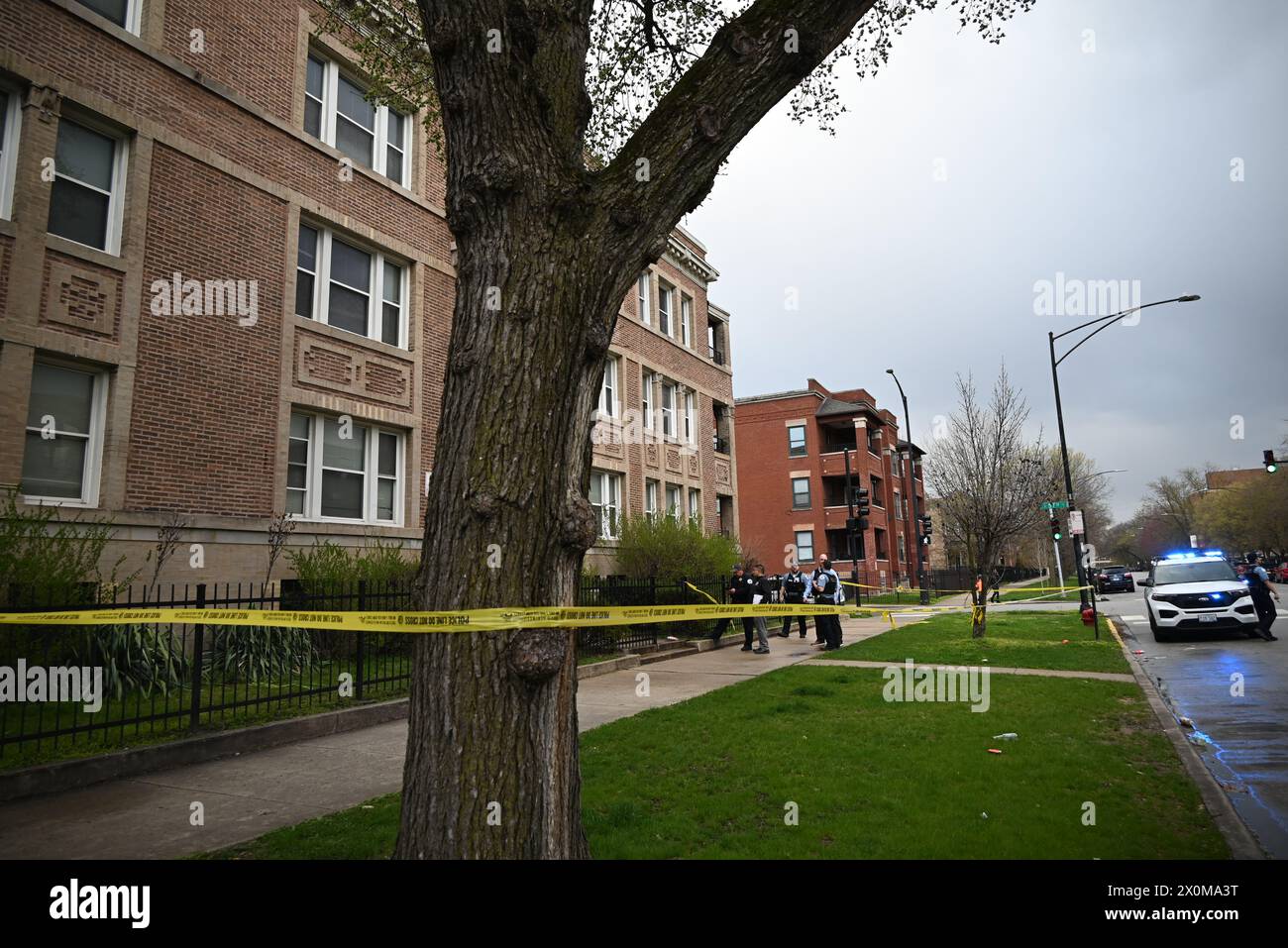 Vehículo policial, oficiales de policía de Chicago y línea de policía no aseguran la escena del crimen, el viernes en Chicago, Illinois, donde un hombre de 46 años fue asesinado a tiros. Hombre de 46 años de edad, asesinado a tiros en el pasillo de un edificio en Chicago, Illinois, Estados Unidos, el 12 de abril de 2024. Aproximadamente a las 4:48 p.m., el viernes, un hombre de 46 años de edad, fue encontrado insensible en el pasillo de un edificio ubicado en la cuadra 5600 de S. Michigan Avenue con una herida de bala en el pecho. La víctima fue transportada al hospital donde fue declarada muerta. No hay información sobre ningún posible sospechoso Foto de stock