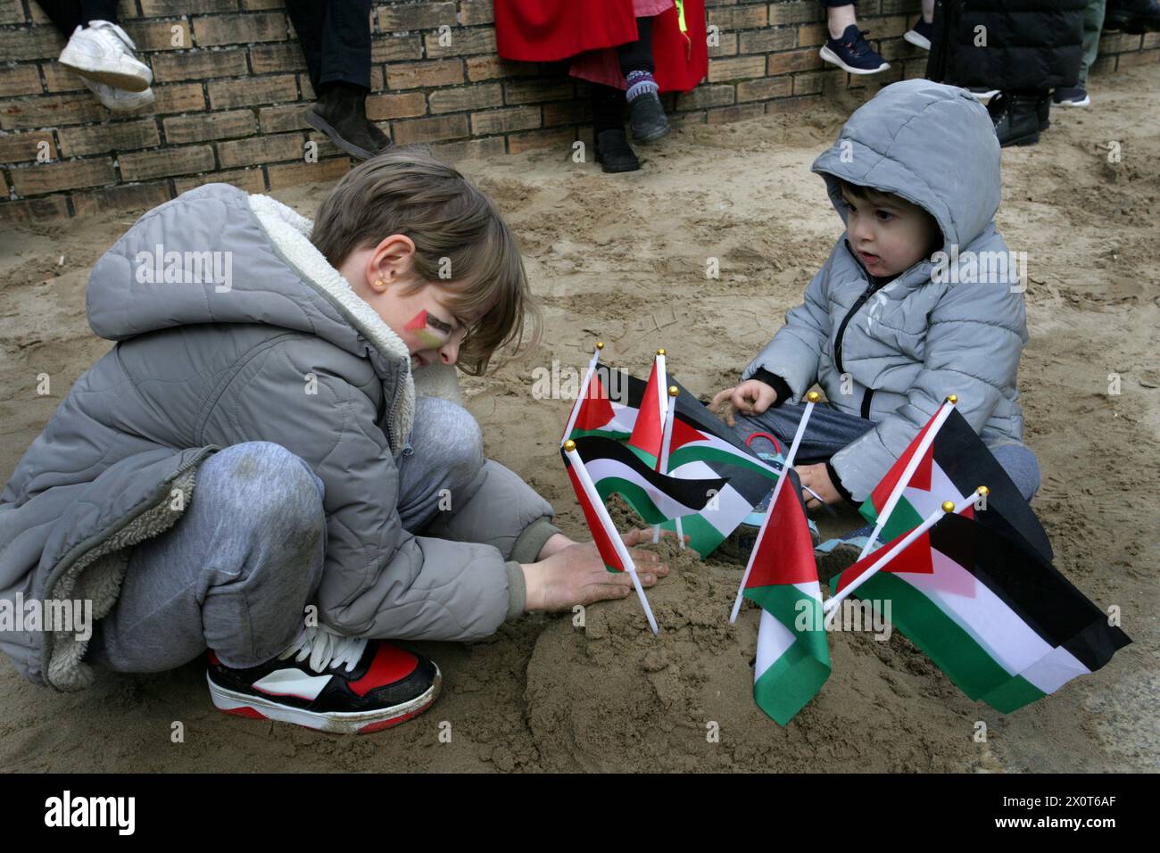 Rhyl, Reino Unido. 13 de abril de 2024. Dos niños pequeños plantan banderas palestinas en una pila de arena durante la manifestación. Más de 150 partidarios pro-palestinos de todo Gales llevaron la protesta a las calles para exigir el cese del fuego en Gaza y detener el genocidio. Crédito: SOPA Images Limited/Alamy Live News Foto de stock