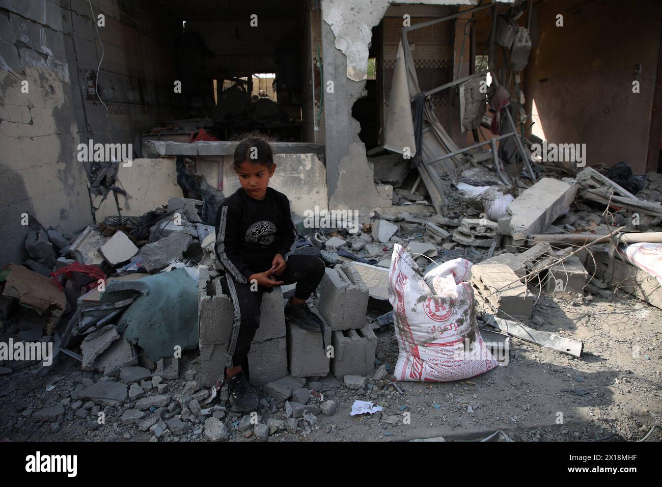Gaza. 15 de abril de 2024. Una niña palestina se sienta frente a una casa destruida en la ciudad de Rafah, al sur de la Franja de Gaza, el 15 de abril de 2024. El número de muertos palestinos por los ataques israelíes en curso en la Franja de Gaza ha aumentado a 33.797, dijo el lunes el Ministerio de Salud de Hamás. Crédito: Khaled Omar/Xinhua/Alamy Live News Foto de stock